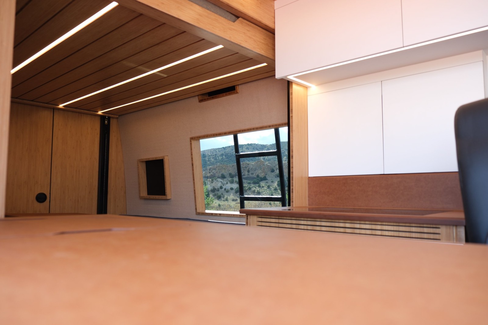 The Den wood countertop and upper cabinets beneath an illuminated slat ceiling.