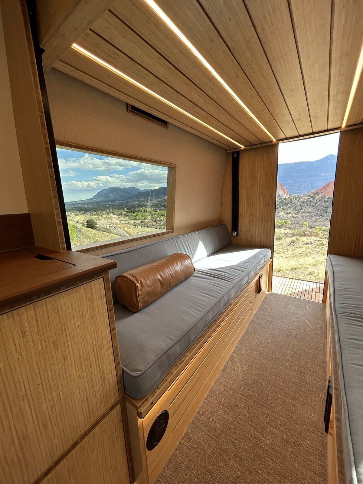 The Den lounge bench beside a mountain-view window and open rear passage.