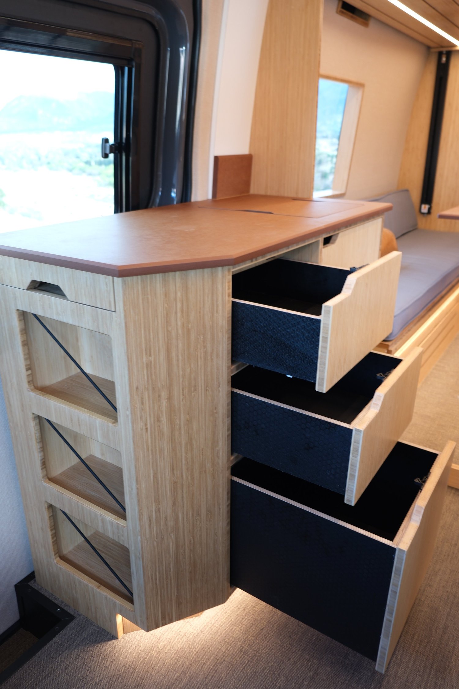 Three open drawers in the Den galley cabinetry beside the rear lounge.
