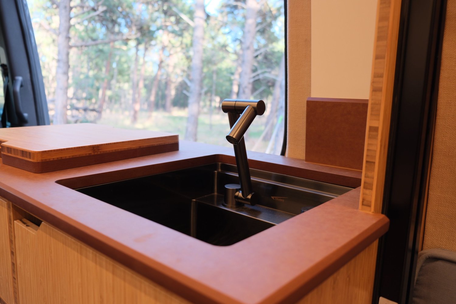 Close-up of The Den’s PaperStone countertop, inset sink, black faucet and wood cutting board.