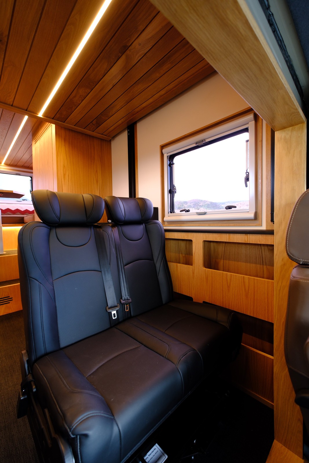 The Nest two-person passenger bench under a window and wood cabinetry.