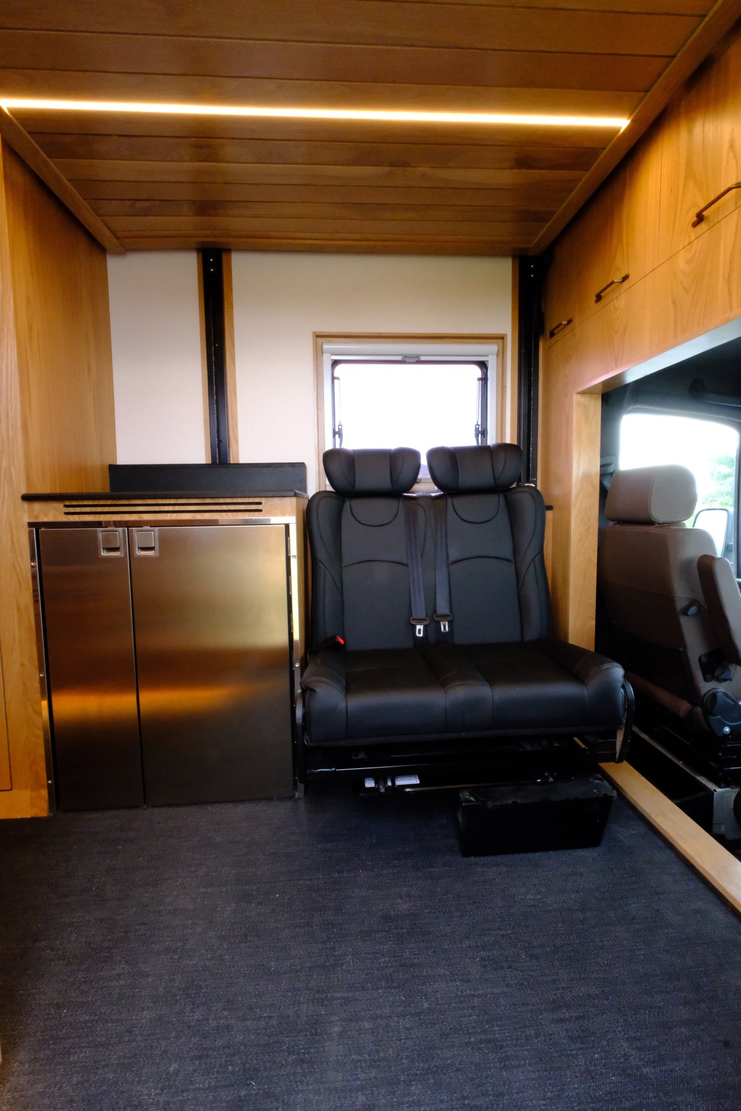 The Nest second-row passenger bench beside the refrigerator and wood cabinetry.